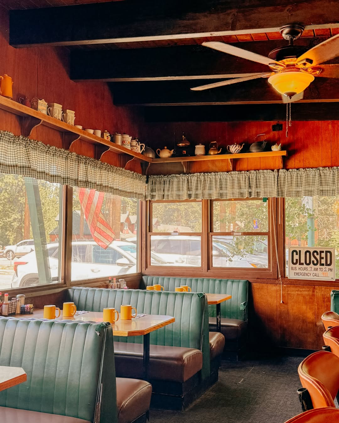 Sunny diner interior with green booths, wooden tables, and a "closed" sign in the window—perfect for reminiscing about your family vacation to Lake Tahoe.