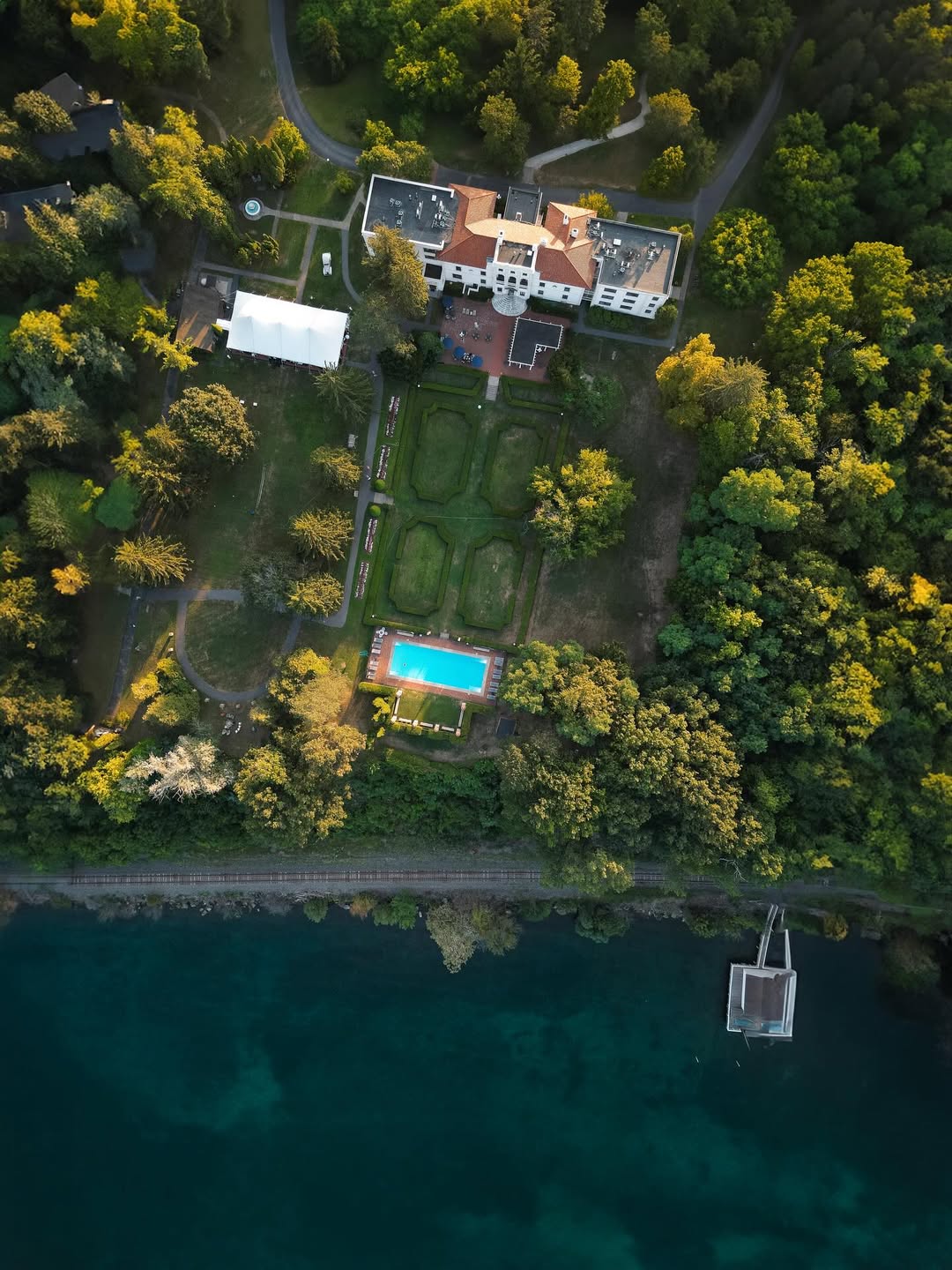 Aerial view of a riverside mansion with gardens, a pool, and surrounding trees—one of the best places to stay in Finger Lakes near wineries.