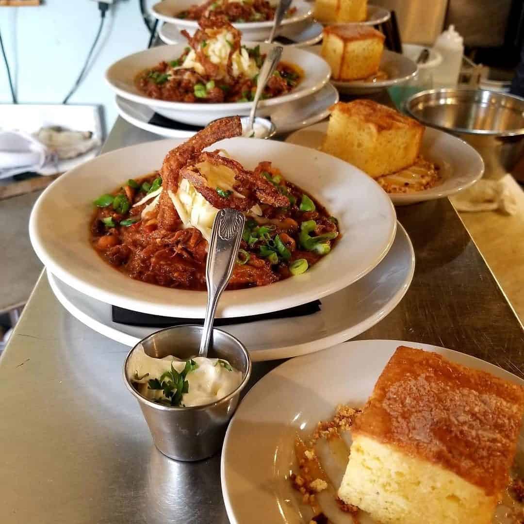 Several plates of food sit on the counter&mdash;cornbread, chili topped with a soft shell crab, and a cup of sour cream&mdash;showcasing the kind of creative fare you might find at Finger Lakes wineries with restaurants.