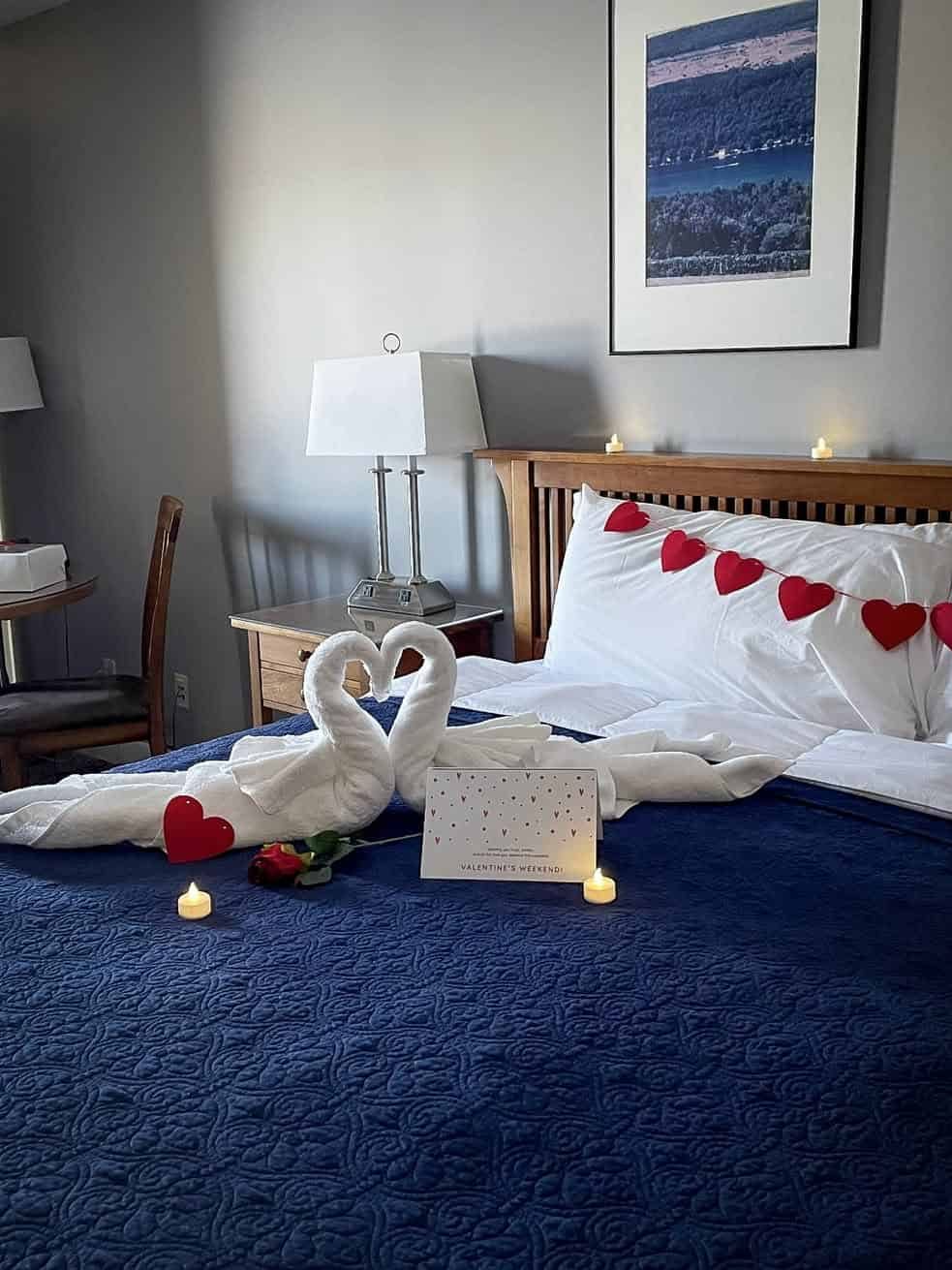 A bed decorated with heart pillows, towel swans, candles, and a rose sets the mood for romance—perfect for couples seeking the Best Places to Stay in Finger Lakes Near Wineries.