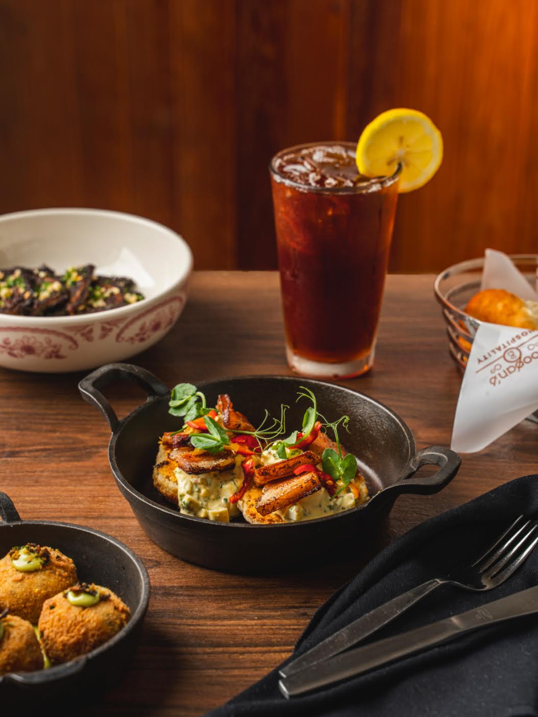 A wooden table with assorted appetizers and a glass of iced tea garnished with a lemon slice—perfect for family dining after exploring things to do in Charleston with kids.