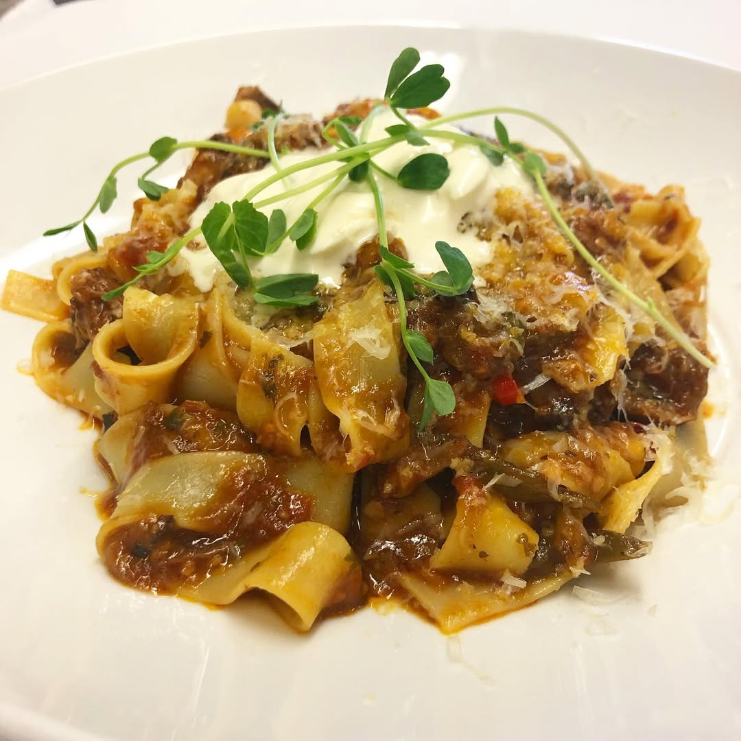 Pappardelle pasta with meat sauce, topped with cream, grated cheese, and fresh microgreens&mdash;an inviting dish reminiscent of those served at Finger Lakes wineries with restaurants.