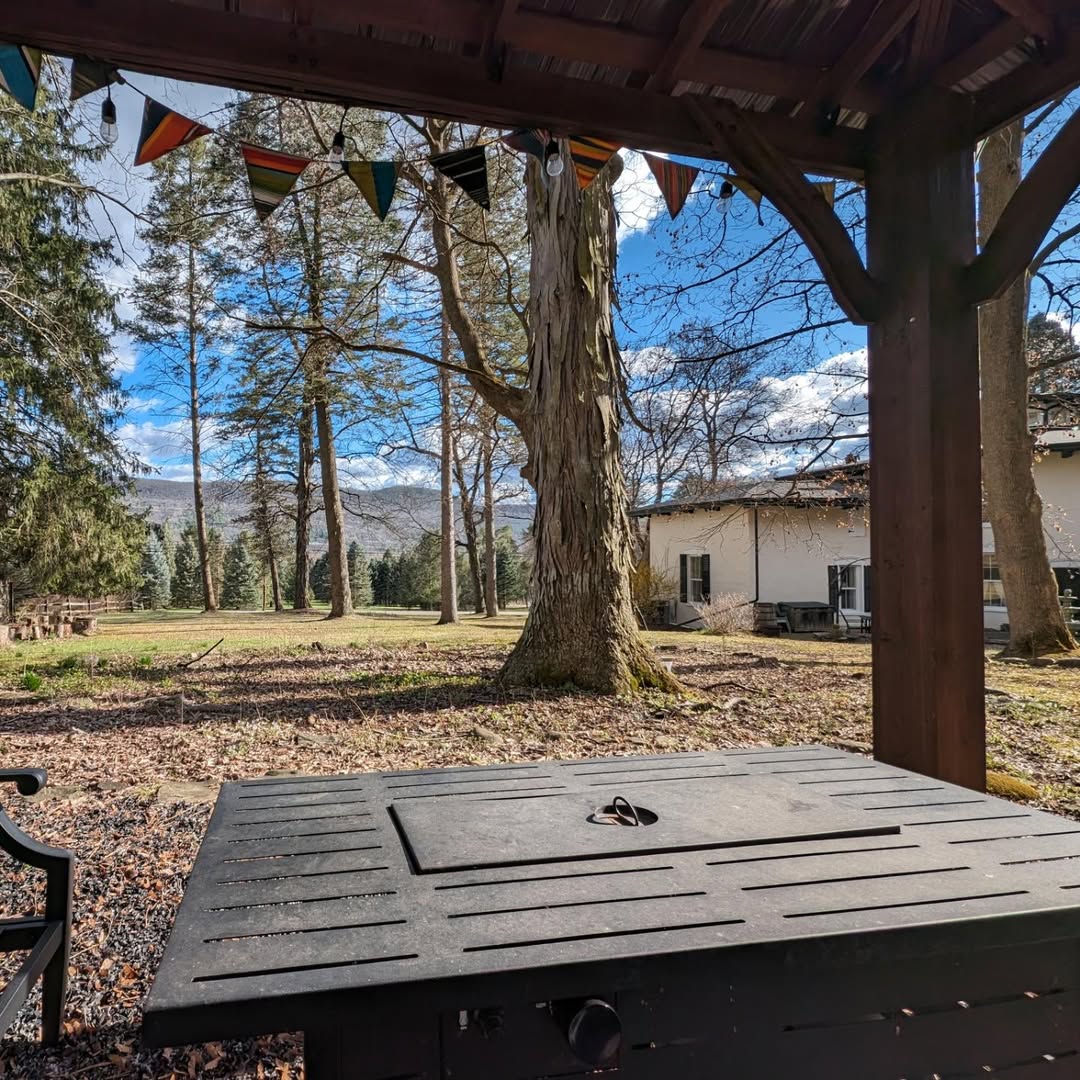 View from under a wooden gazebo facing a grassy yard with trees and a house in the background—one of the best places to stay in Finger Lakes near wineries, offering peaceful scenery and relaxing charm.