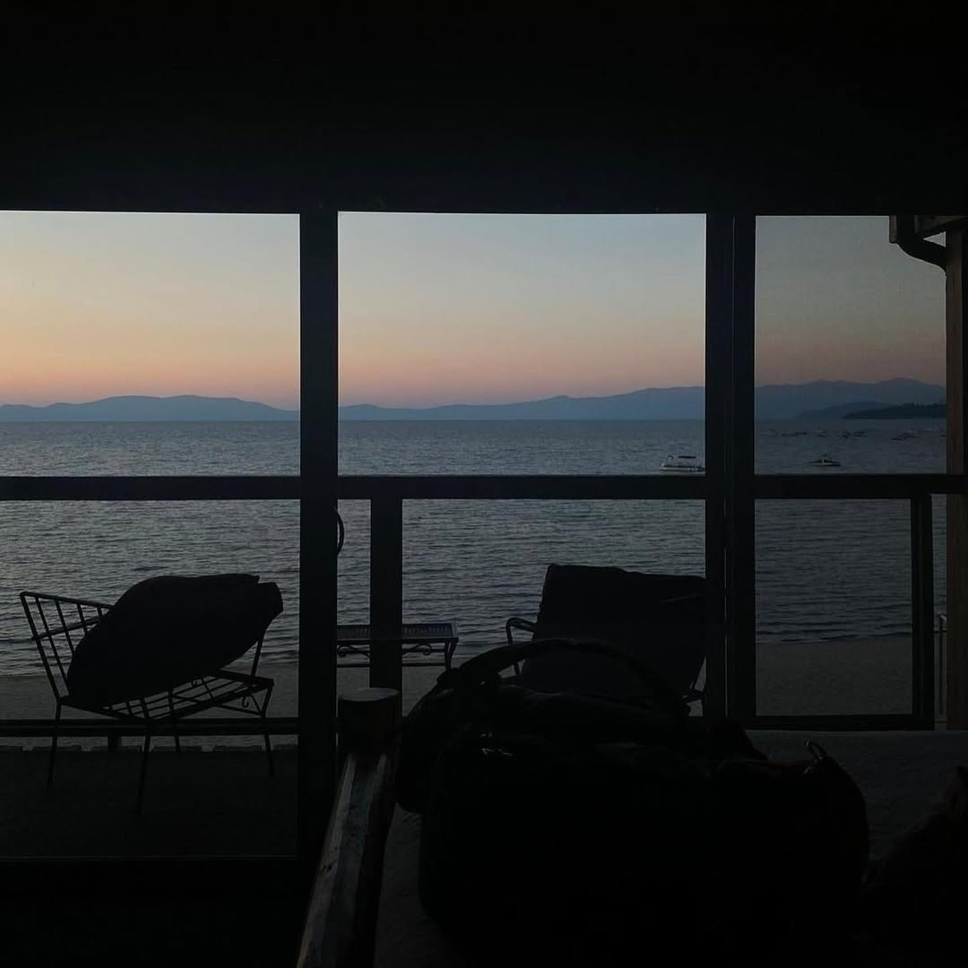 Silhouettes of chairs on a porch overlook a calm lake at sunset, with mountains in the distance—capturing the peaceful spirit of a family vacation to Lake Tahoe.