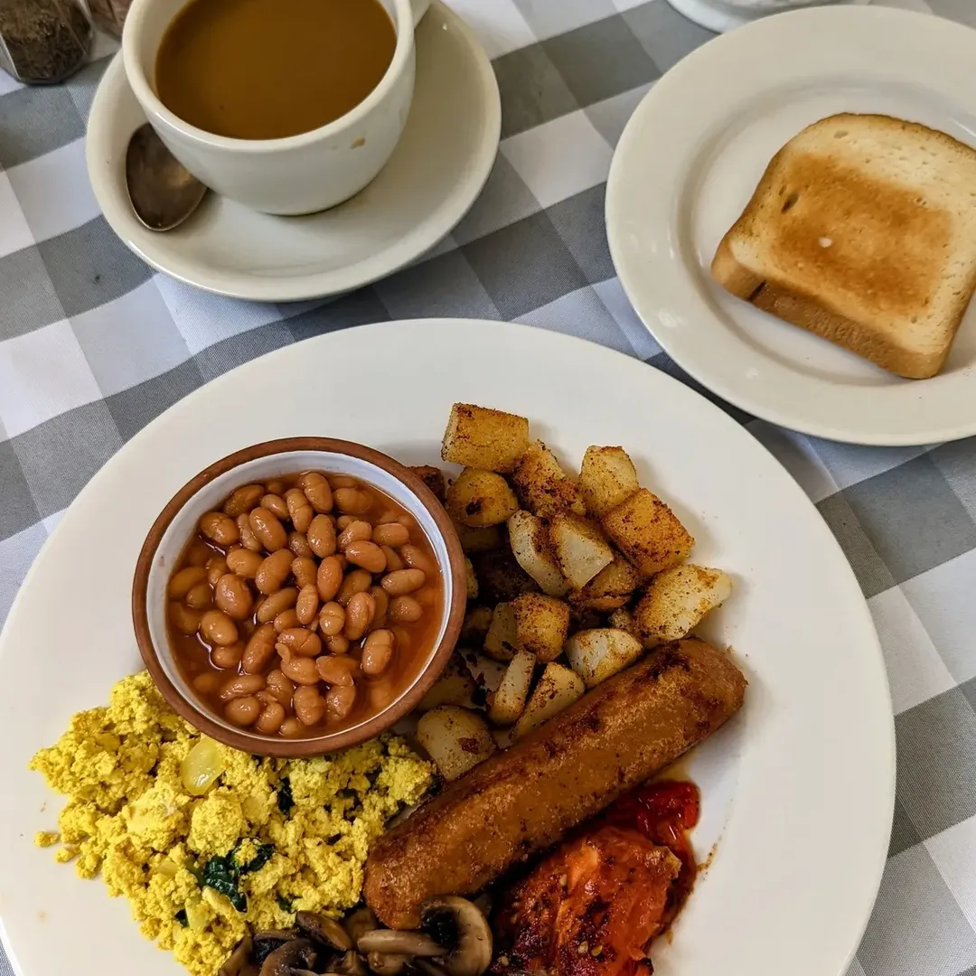 A plate with beans, tofu scramble, potatoes, sausage, mushrooms, toast, and a cup of soup on a checkered tablecloth—perfect fuel before exploring the Best Places to Stay in Finger Lakes Near Wineries.