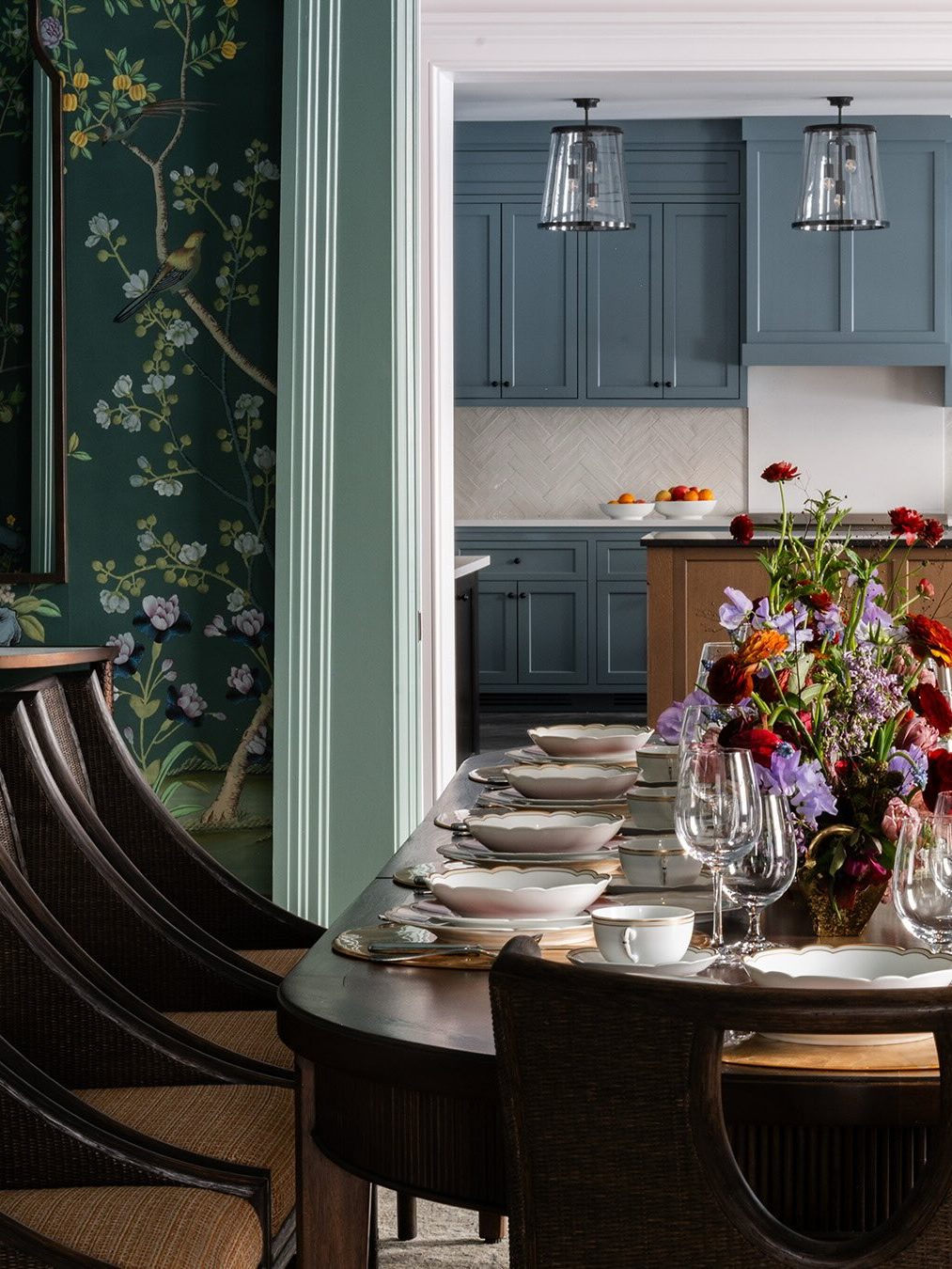 Elegant dining table set with flowers, view into a kitchen with blue cabinets and pendant lights—perfect for those seeking the Best Places to Stay in Finger Lakes Near Wineries.