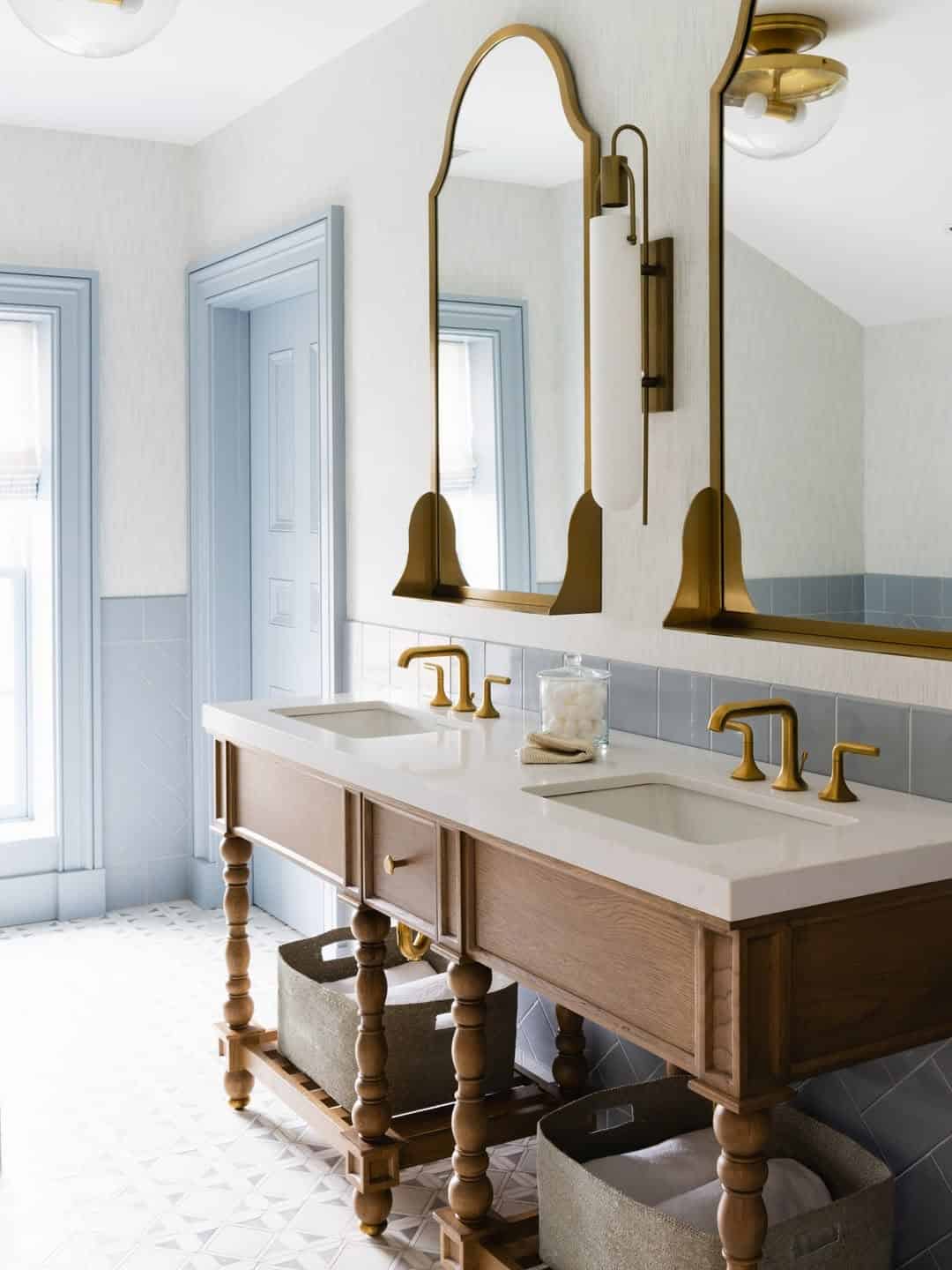 Elegant bathroom with double sinks, gold fixtures, matching mirrors, and light blue accents—one of the best places to stay in Finger Lakes near wineries.