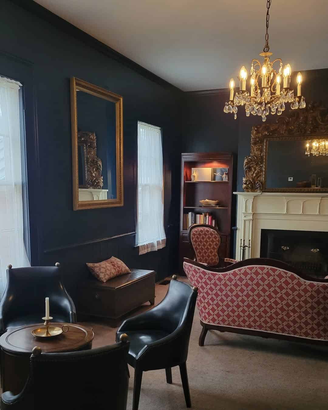 Elegant vintage living room with chandelier, dark walls, antique mirror, and red patterned furniture—perfect for those seeking the Best Places to Stay in Finger Lakes Near Wineries.