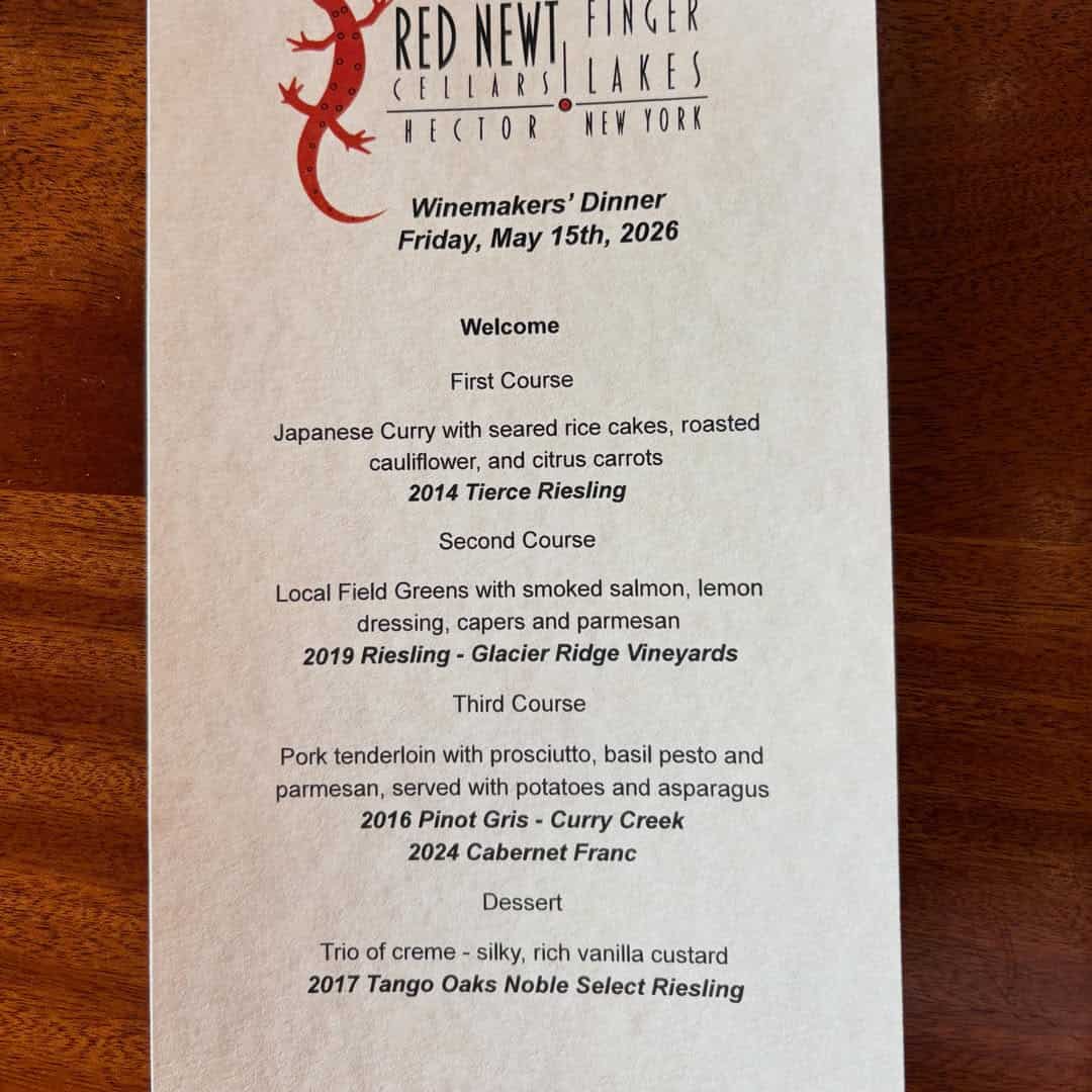 Menu for a Winemakers&rsquo; Dinner, featuring three courses with curated wine pairings from Finger Lakes wineries, presented elegantly on a wooden table. Discover the flavors of renowned Finger Lakes restaurants and wineries with each dish.