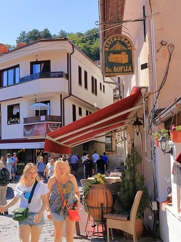 Vibrant street scene in a European village with shops and tourists.