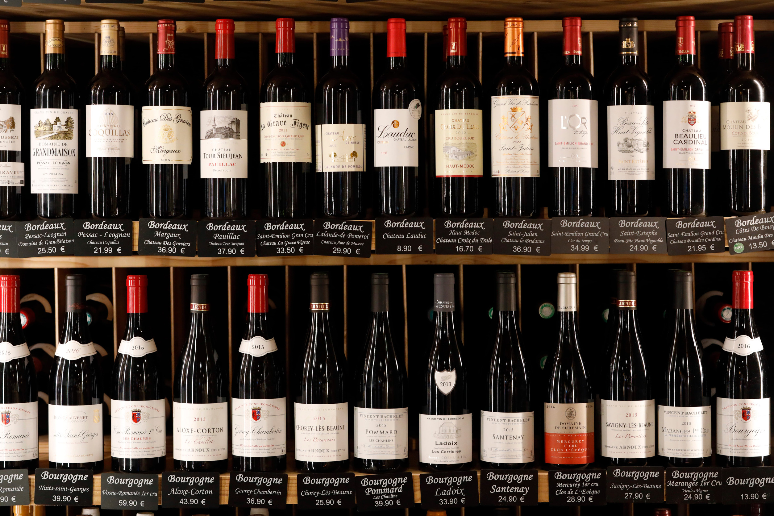 Rows of assorted wine bottles with labels, displayed on shelves in a wine shop&mdash;an inviting scene for those passionate about wine tourism.