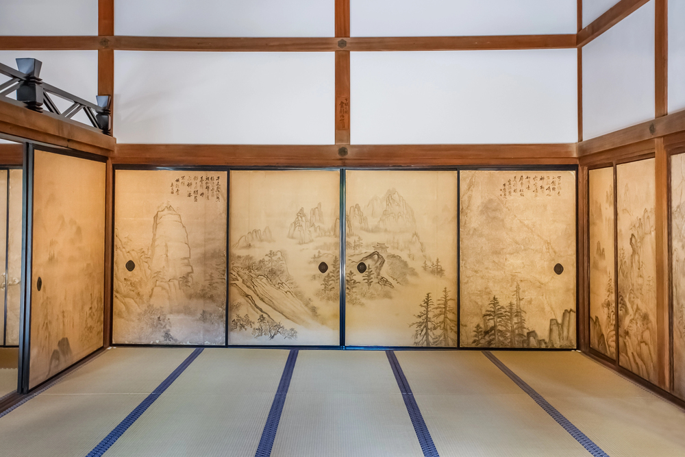 Traditional Japanese tatami room with sliding doors featuring landscape art and wooden beams, evoking the serene atmosphere often experienced while traveling in Japan.