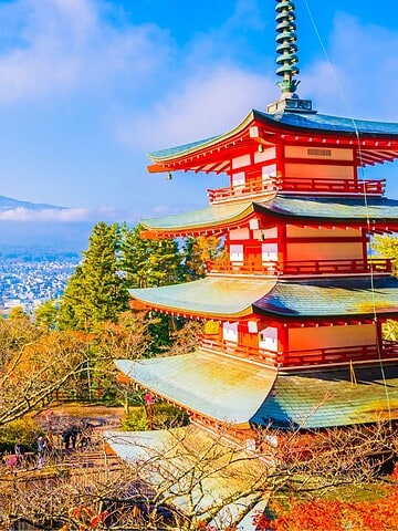 A red pagoda with Mount Fuji in the background, surrounded by colorful autumn trees under a blue sky—an iconic scene that captures the beauty of traveling in Japan.