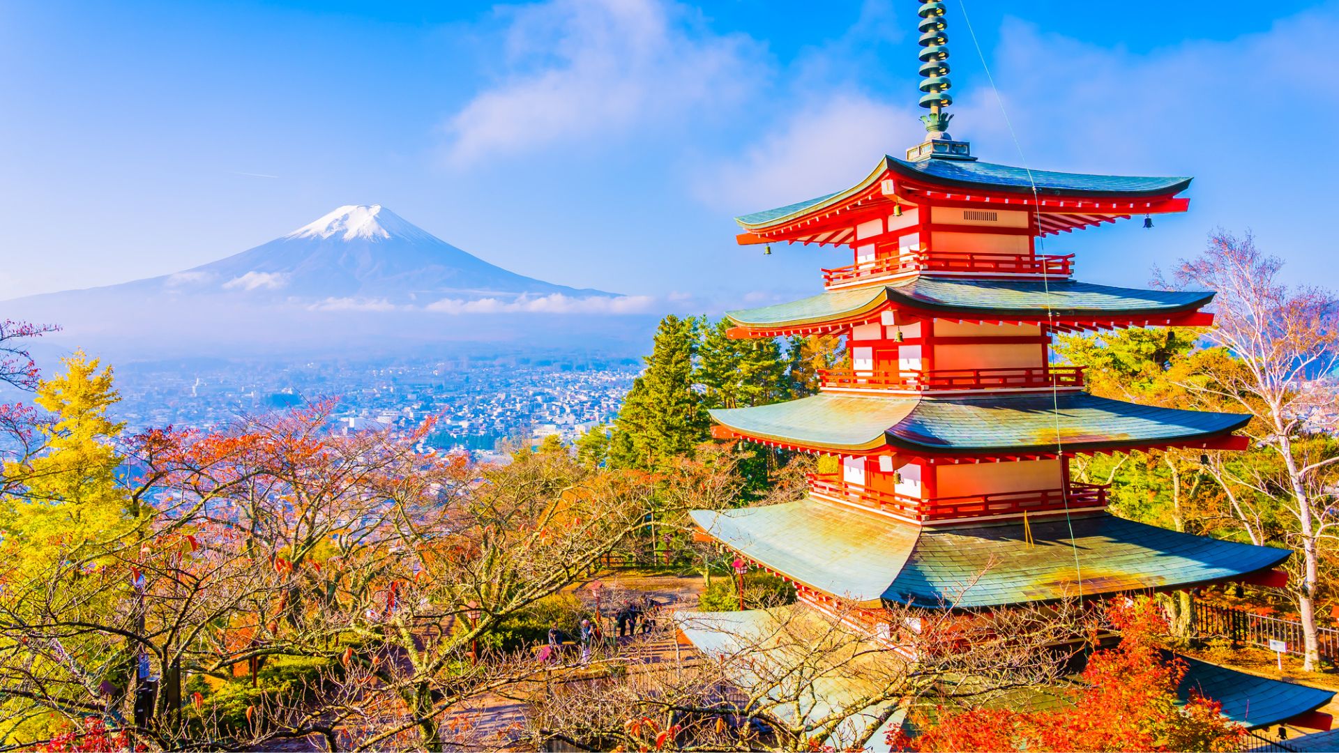 A red pagoda with Mount Fuji in the background, surrounded by colorful autumn trees under a blue sky—an iconic scene that captures the beauty of traveling in Japan.