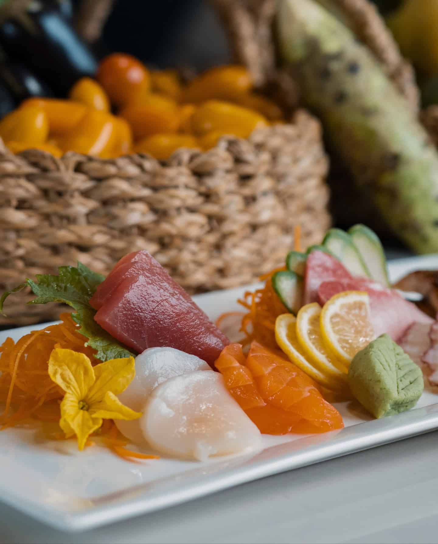Sashimi platter with tuna, salmon, scallop, lemon slices, wasabi, and garnish on a white plate&mdash;an exquisite culinary experience perfect for those seeking Grand Cayman luxury travel.