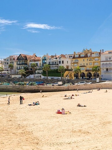 Scenic beach with colorful town buildings and people enjoying summer day.