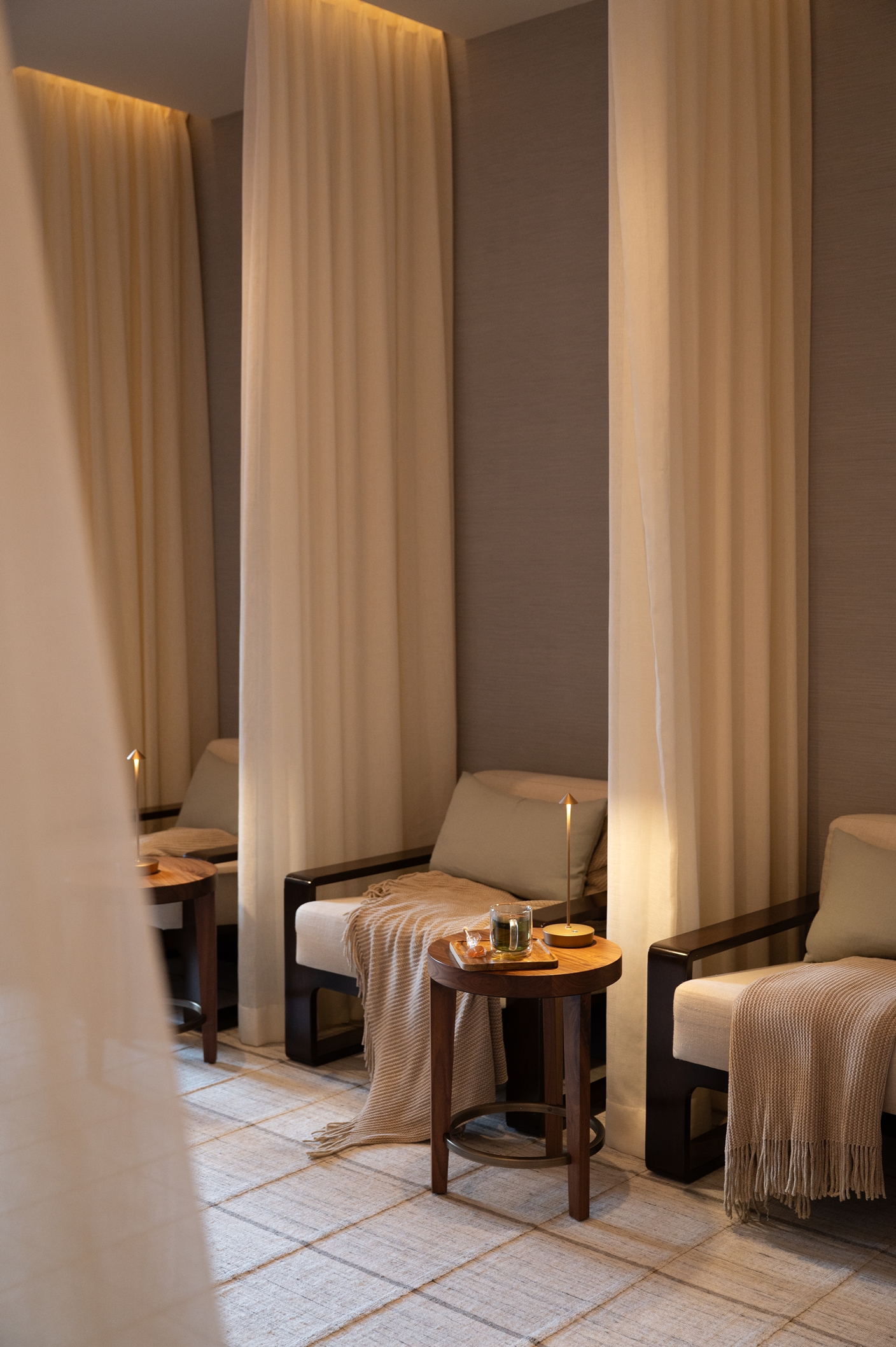 Two cozy armchairs with blankets, small tables with candles and tea, and soft lighting create a relaxing space reminiscent of the inviting ambiance at the Rusty Parrot Lodge and Spa.