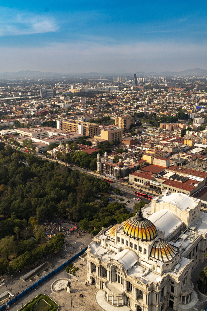 Aerial view of Palacio de Bellas Artes with surrounding cityscape and park under a blue sky, showcasing one of Mexico City&rsquo;s top european destination dupes.