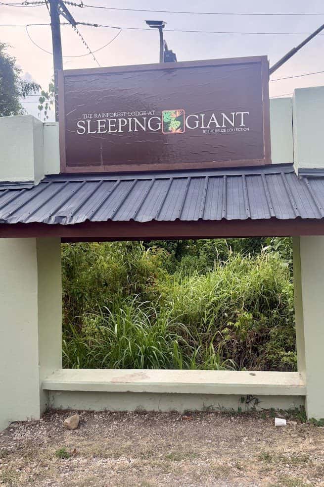 A sign for The Rainforest Lodge at Sleeping Giant stands above a green wall with grass in the background, offering a welcoming first impression that sets the stage for any thoughtful The Rainforest Lodge at Sleeping Giant review.