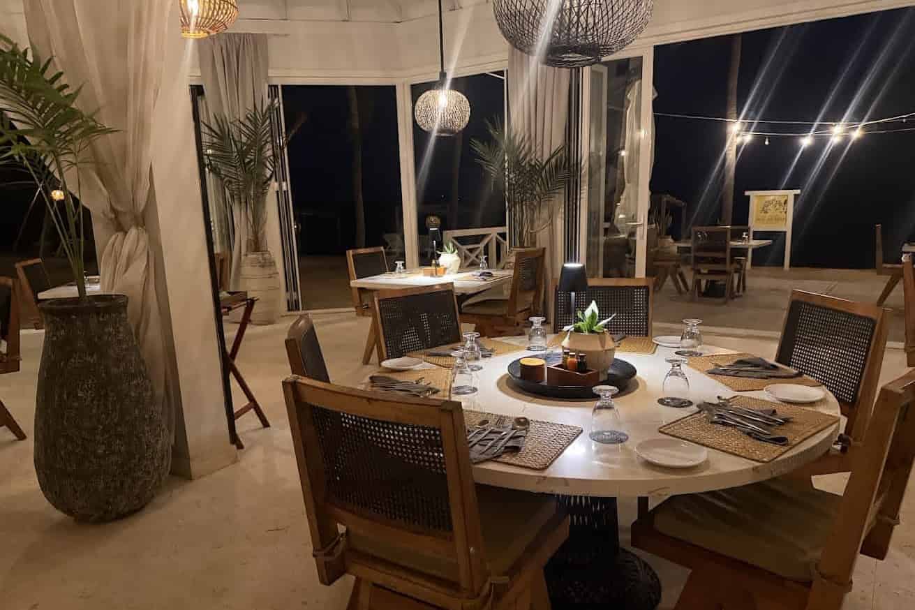 Cozy restaurant at night with wooden tables, chairs, and warm lighting, set for dinner&mdash;an inviting atmosphere reminiscent of glowing evenings described in many a The Lodge at Jaguar Reef review.