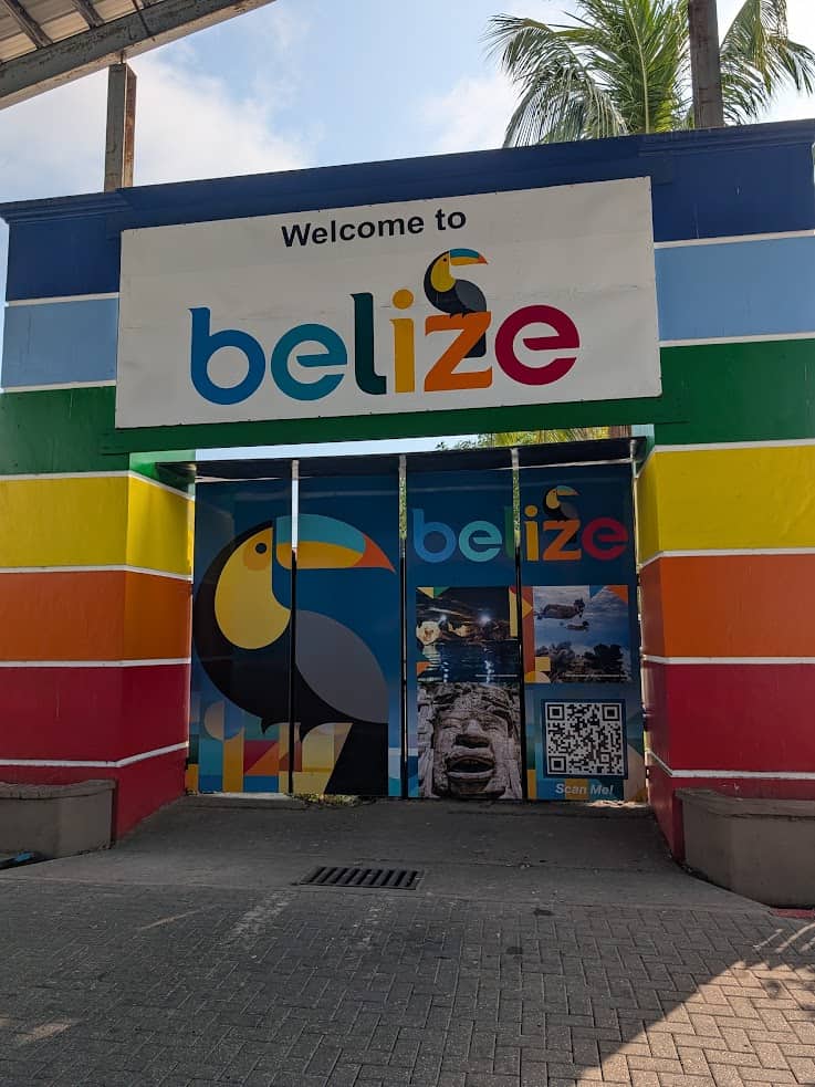 Colorful &ldquo;Welcome to Belize&rdquo; entrance with toucan images, rainbow stripes, and a QR code on the doors&mdash;offering the perfect start to your belize reef and ruins trip.