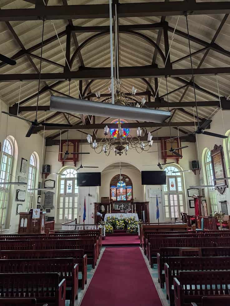Interior of a church with pews, stained glass windows, chandeliers, and altar decorated with flowers&mdash;an atmosphere as serene and inspiring as memories from a Belize reef and ruins trip.