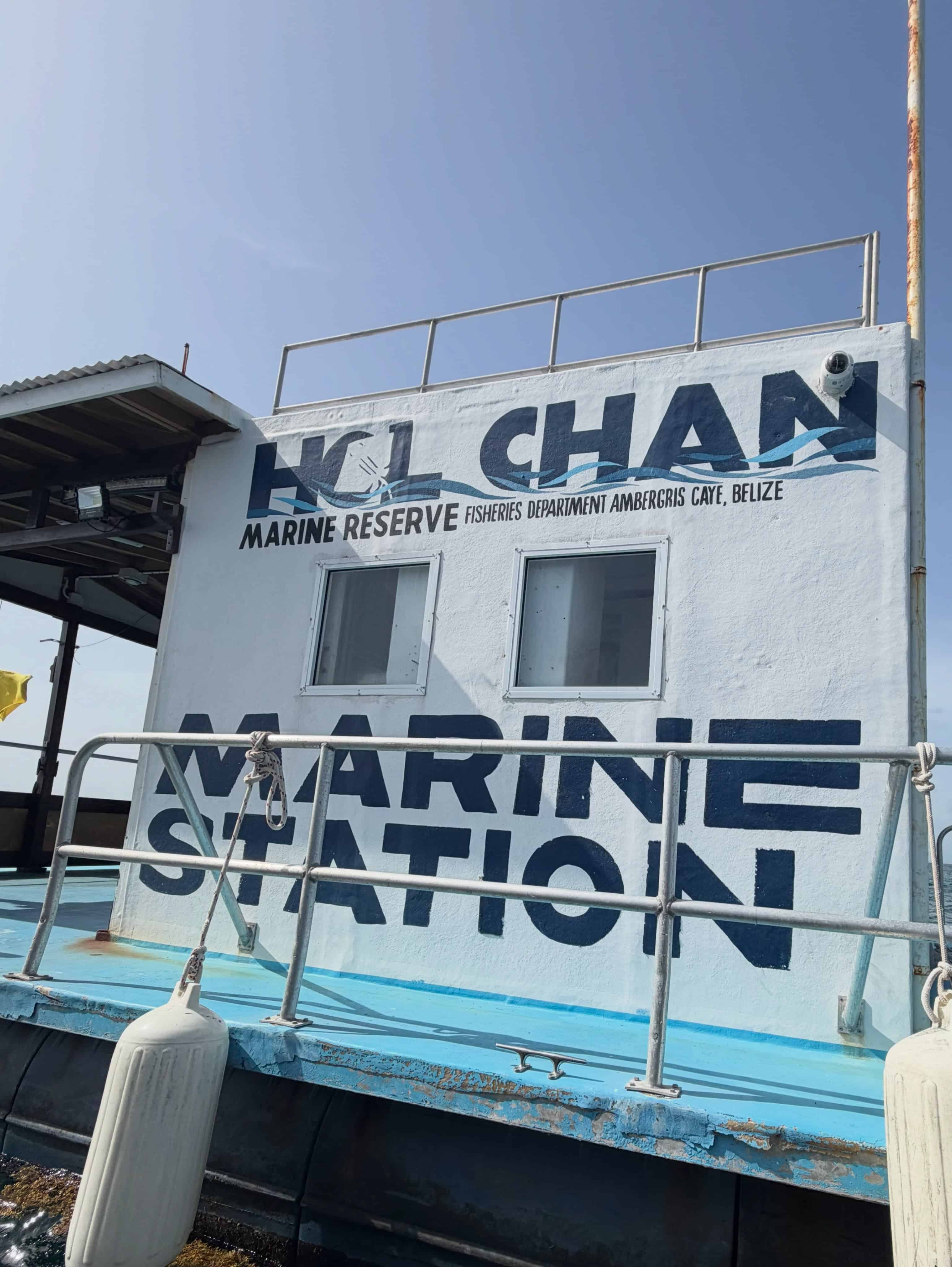 A white marine station building with &ldquo;Hol Chan Marine Reserve&rdquo; painted on the side, under a clear sky&mdash;an iconic starting point for those embarking on a Belize reef and ruins trip.