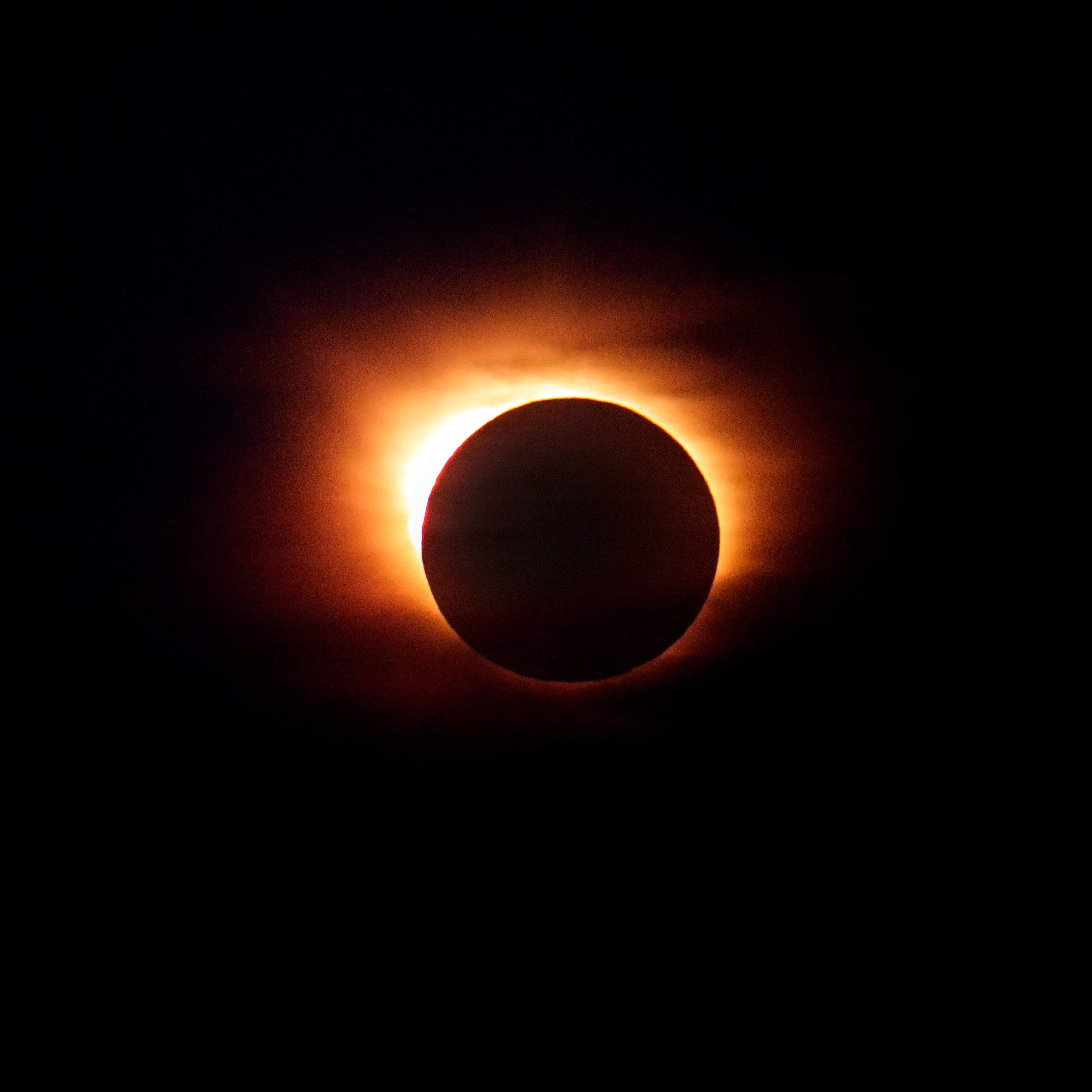 A total solar eclipse with a glowing corona visible behind the dark silhouette of the moon, as experienced from a Solar Eclipse Cruise.