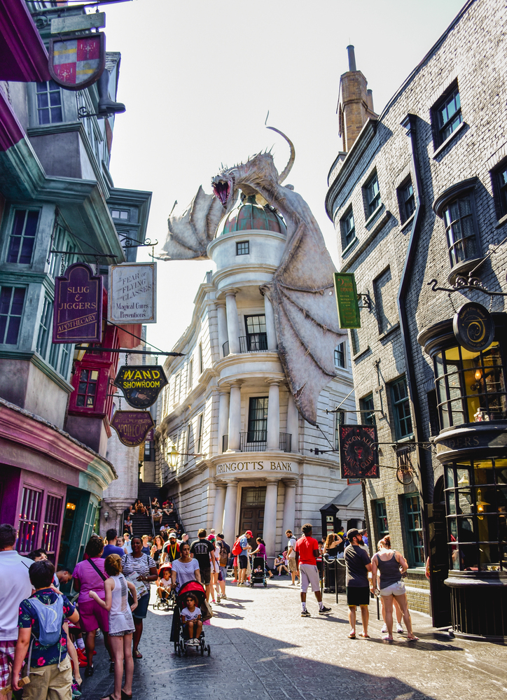 Crowds walk past Gringotts Bank with a large dragon perched on the roof in a themed Harry Potter street, making it one of the top things to do in Orlando with kids.