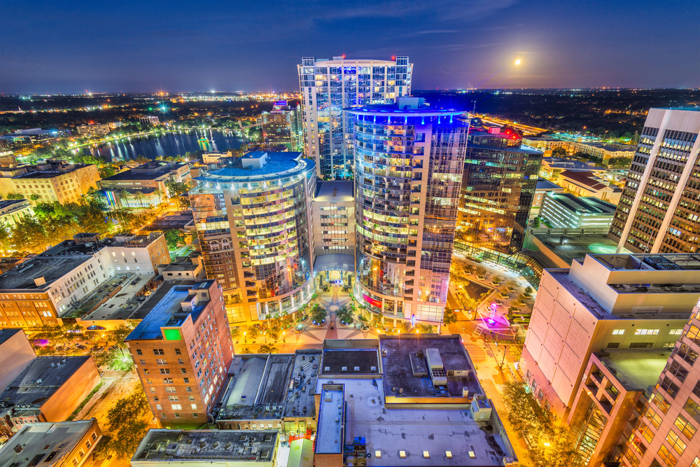 Downtown cityscape at night with tall buildings, bright lights, and a full moon in the sky—perfectly capturing the vibrant energy you’ll find when exploring things to do in Orlando with kids.