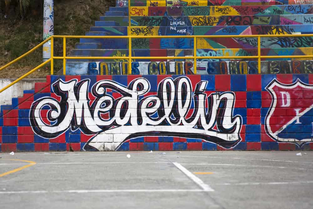 Medellín“ painted in large white graffiti letters on colorful bleachers and a wall at an outdoor sports court—a vibrant spot that’s perfect for families exploring fun Things to Do in Medellin with Kids.