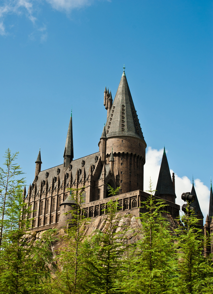 A large stone castle with multiple tall towers rises above green trees under a clear blue sky—an enchanting sight that feels straight out of a fairytale and one of the delightful things to do in Orlando with kids.