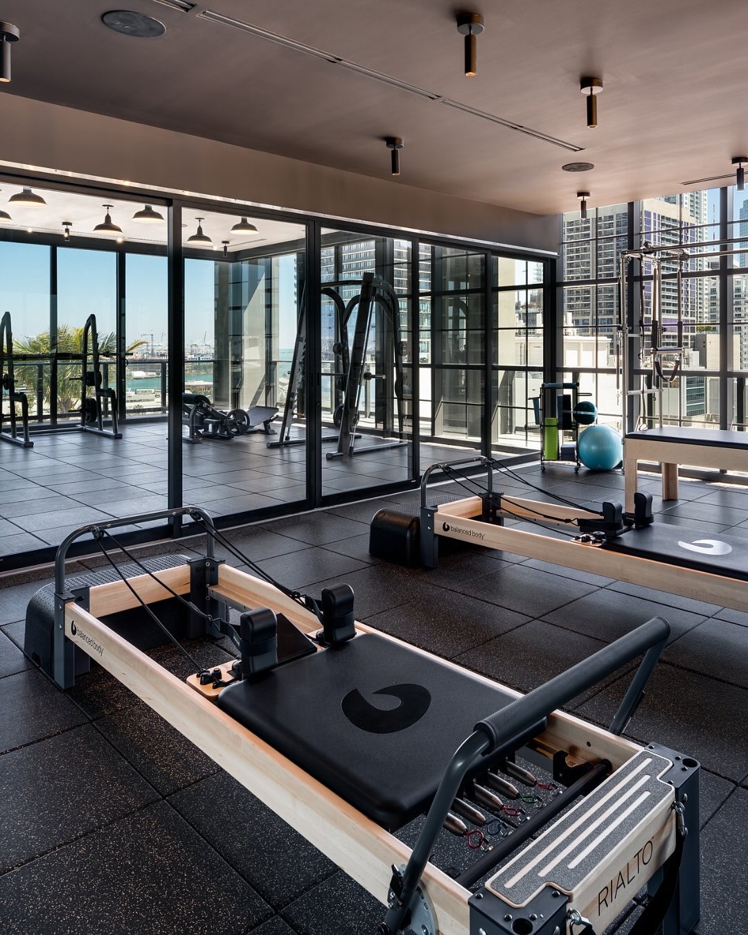 Modern gym with reformer Pilates machines, large mirrors, and city views through floor-to-ceiling windows—an impressive wellness space highlighted in many Gale Miami Hotel & Residences reviews.