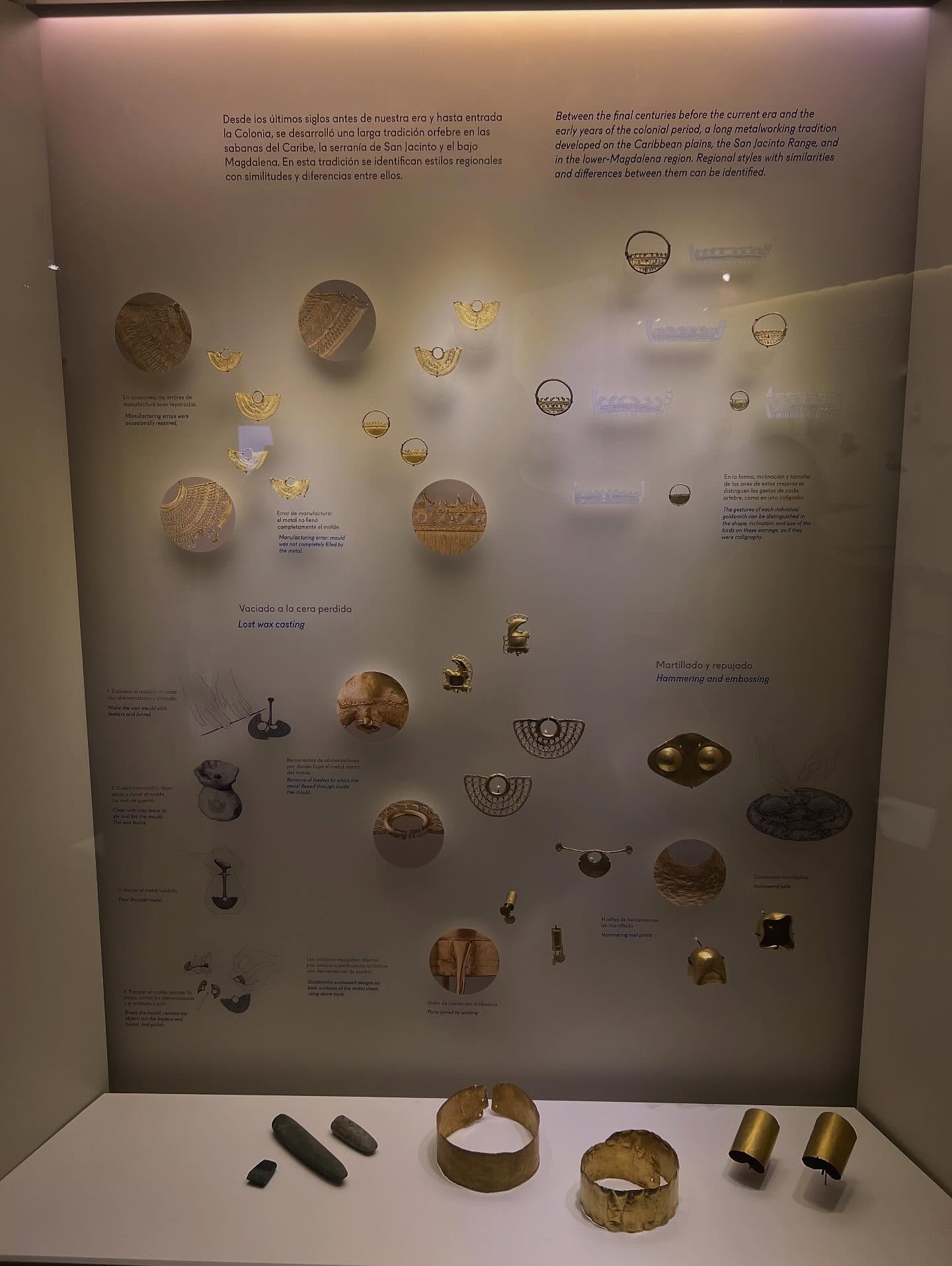 Display case with ancient gold jewelry, artifacts, and descriptions in Spanish and English on a grey background&mdash;one of the fascinating things to do in Cartagena for history enthusiasts.