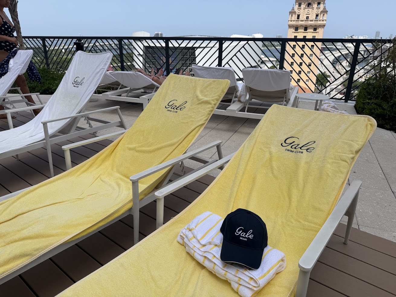 Yellow lounge chairs by a pool, with a folded towel and a navy Gale cap placed on one chair, set the scene for a relaxing afternoon often highlighted in many Gale Miami Hotel & Residences reviews.