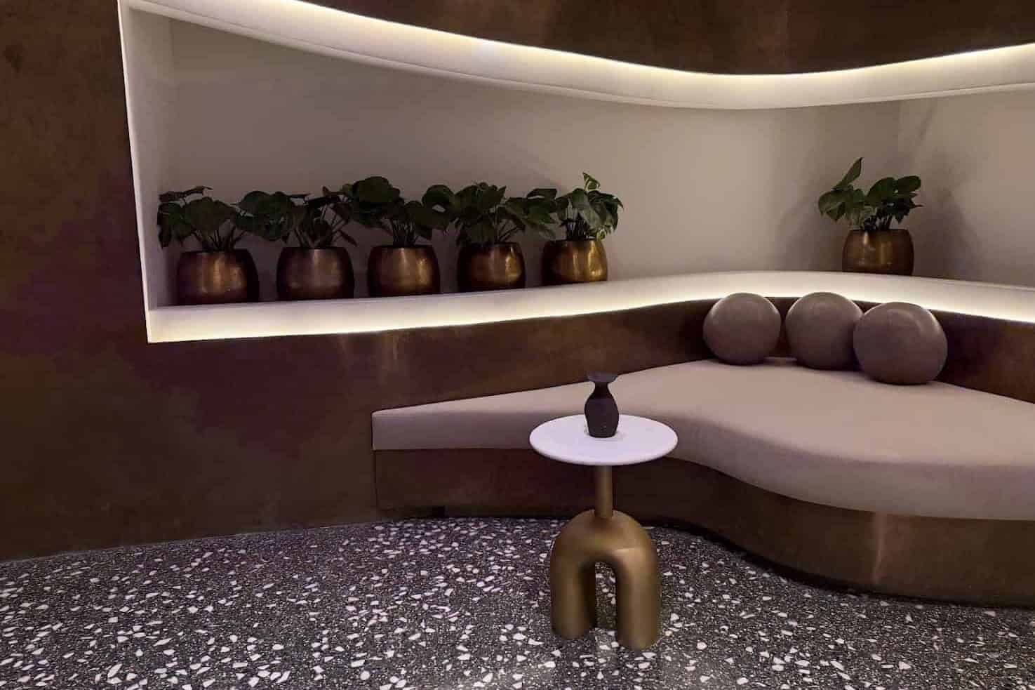 Curved seating area with a pedestal table, plants, and pillows, as seen in the Seia Miami review.