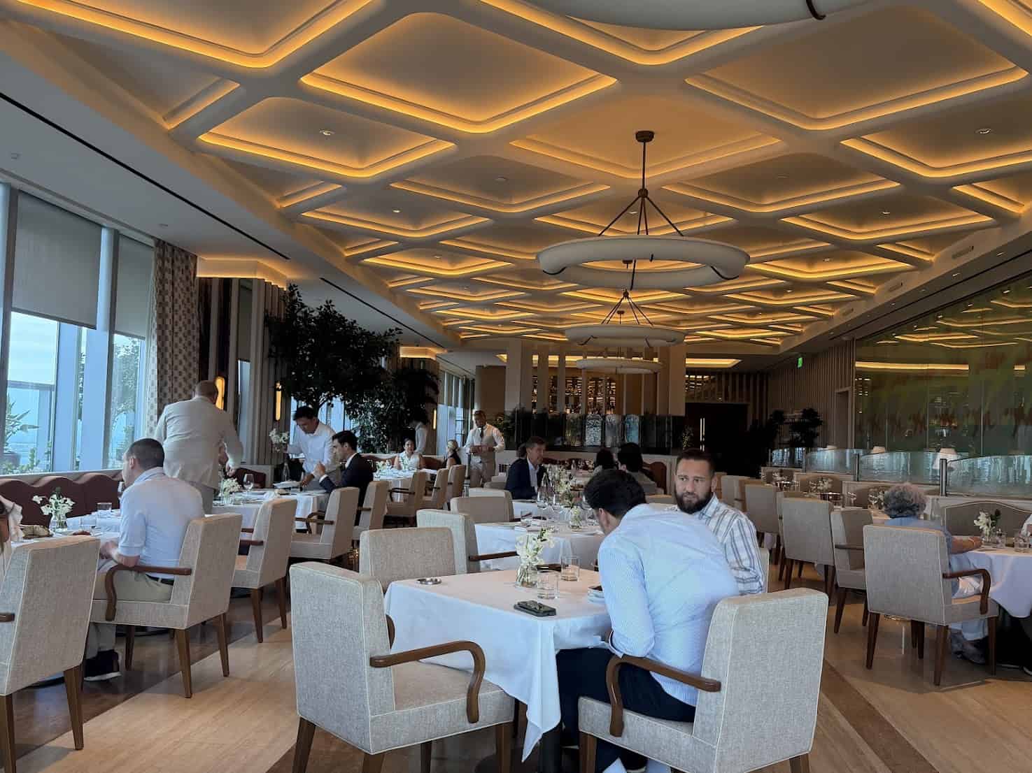 Diners at tables in a modern restaurant with a geometric ceiling, captured in this Seia Miami review.
