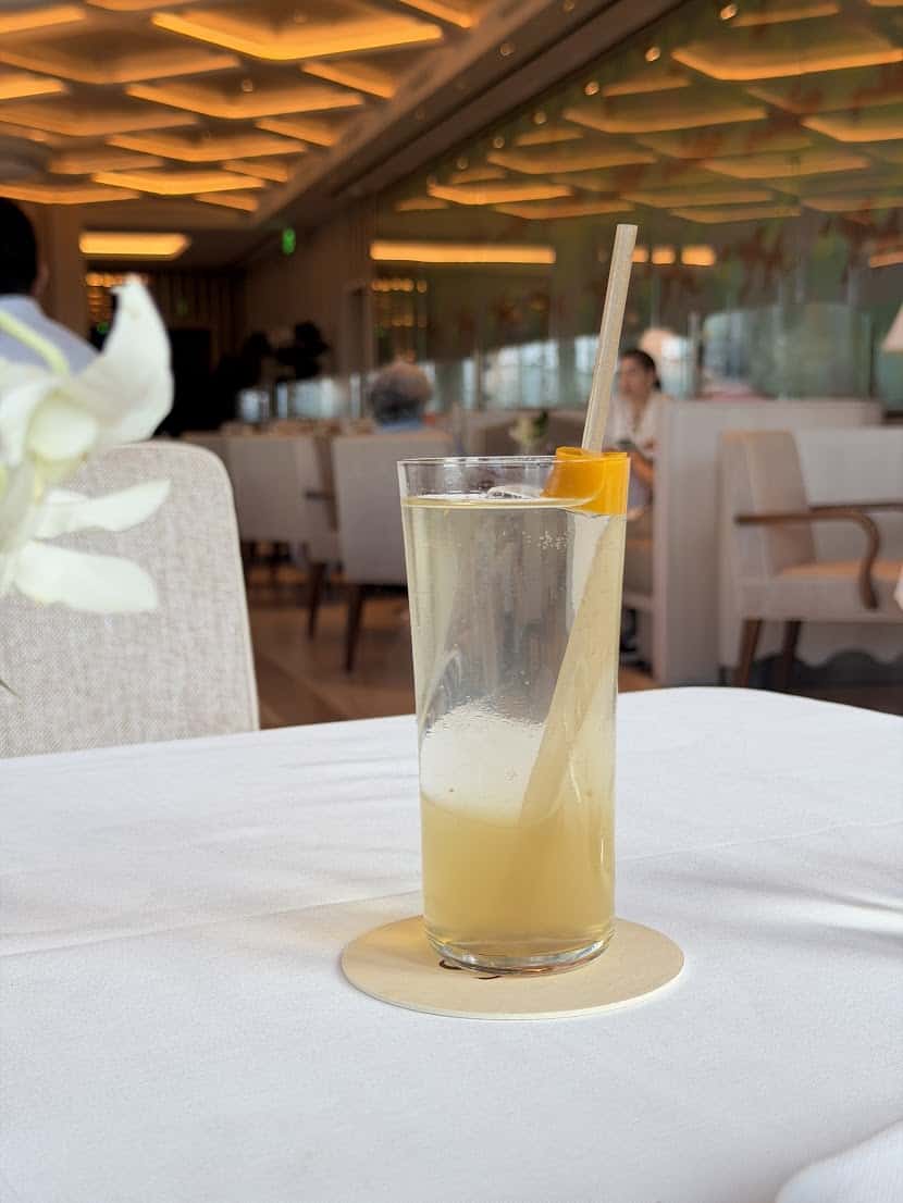 A glass of pale iced tea with an orange garnish on a white tablecloth, as seen in our Seia Miami review.