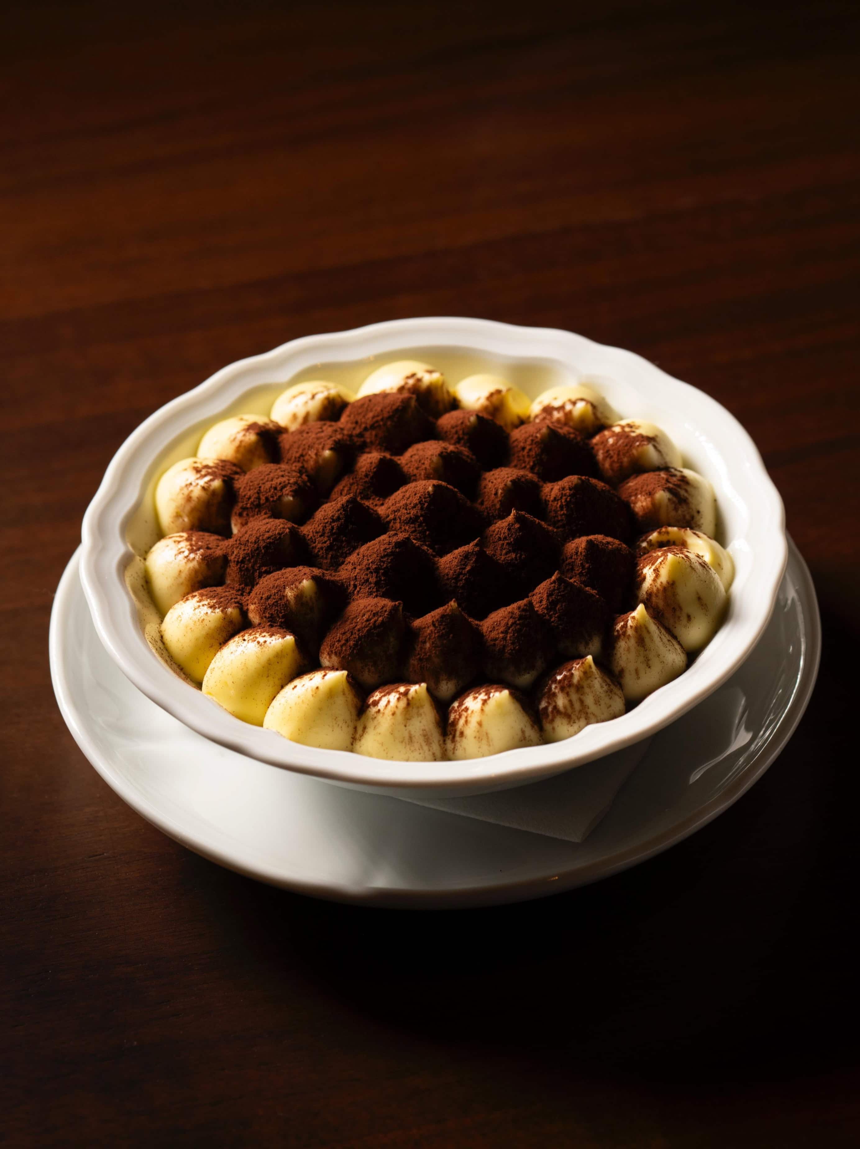 A white bowl of tiramisu topped with cocoa powder from the Seia Miami review.